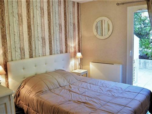 une chambre avec un lit et un miroir au mur dans l'établissement Appartement Climatisé 4 Pièces avec Jardin, à 200m de la Plage - Le Lavandou, Cavalière - FR-1-251-568, au Lavandou