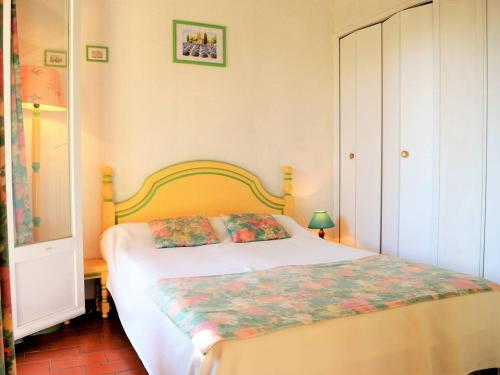 a bedroom with a bed with a floral blanket on it at Appartement Le Lavandou, 2 pièces, 4 personnes - FR-1-251-573 in Le Lavandou