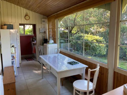 - une cuisine avec une table blanche et 2 fenêtres dans l'établissement Maison de Charme pour 6 à Biscarrosse-Plage, Proche Centre, Jardin, BBQ, Non-Fumeur, Animaux Non Admis - FR-1-521-229, à Biscarrosse