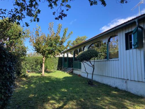 une maison avec une cour à côté d'un bâtiment dans l'établissement Maison de Charme pour 6 à Biscarrosse-Plage, Proche Centre, Jardin, BBQ, Non-Fumeur, Animaux Non Admis - FR-1-521-229, à Biscarrosse