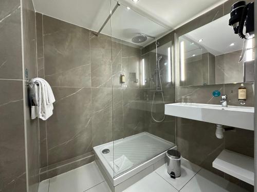 ein Bad mit einer Dusche und einem Waschbecken in der Unterkunft Hôtel Exsel Créolia in Saint-Denis