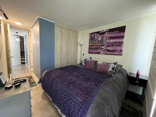 a bedroom with a large bed with a purple bedspread at Departamento Lagunamar con patio privado in Las Cruces
