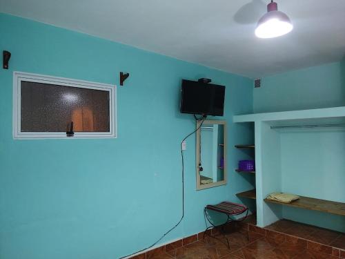 Habitación con pared azul y TV de pantalla plana. en La Norteña tres cerritos 2 en Salta