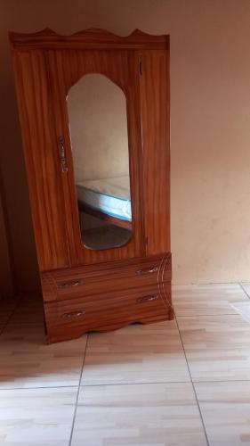 a wooden cabinet with a mirror in a room at Liz One Stop Apartment in Georgetown