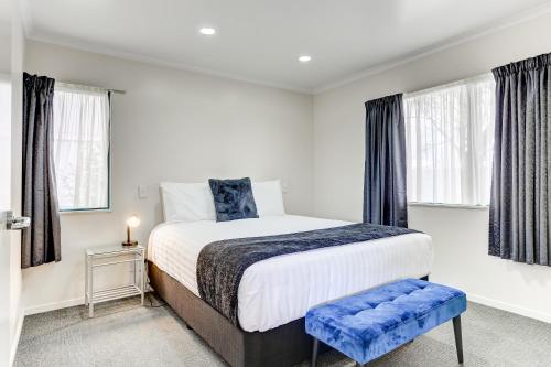 a bedroom with a large bed and two windows at ASURE Cooks Gardens Motor Lodge in Whanganui