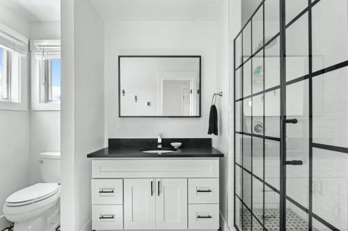 a bathroom with a sink and a toilet and a mirror at Poolside Chic by the Sea - Ocean Bay Park, NY in Ocean Beach