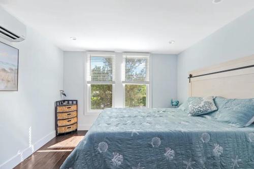 a bedroom with a bed and two windows at Poolside Chic by the Sea - Ocean Bay Park, NY in Ocean Beach