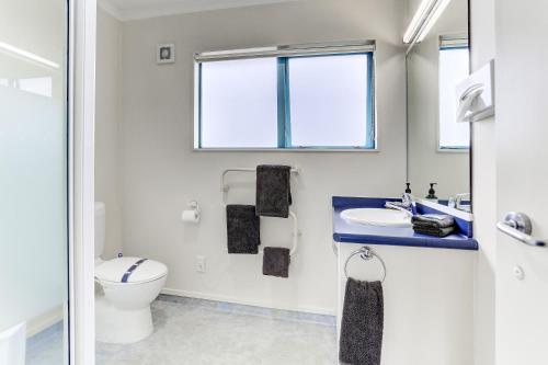 a bathroom with a toilet and a sink and a window at ASURE Cooks Gardens Motor Lodge in Whanganui