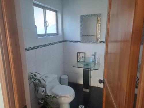 een badkamer met een toilet, een wastafel en een raam bij Casa en Tomé con piscina, vista al mar, equipada. in Concepción