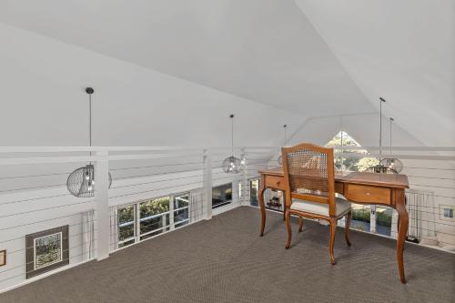 a desk and chair in a room with windows at Braeside, Kangaroo Valley in Kangaroo Valley