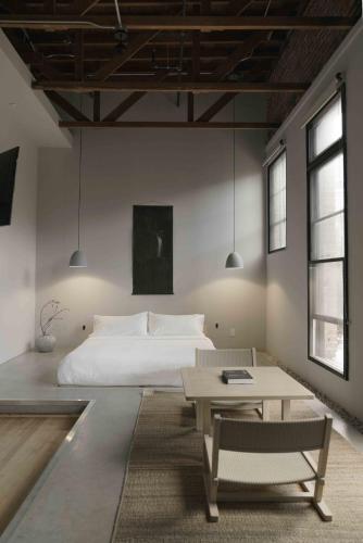 a bedroom with a white bed and a table at kodō hotel - Heart of LA Arts District in Los Angeles