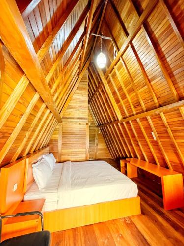 a bedroom with a bed in a wooden room at ANARA VILLA SAMOSIR MANAGED BY 3 SMART HOTEL in Sinapuran