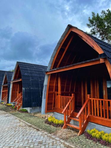 a wooden barn with a black roof and a porch at ANARA VILLA SAMOSIR MANAGED BY 3 SMART HOTEL in Sinapuran