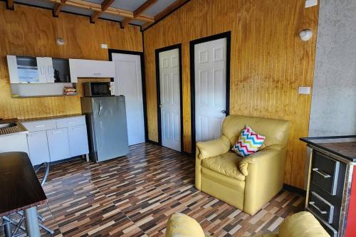 ein Wohnzimmer mit einem Stuhl und eine Küche in der Unterkunft Cabaña buck in Dalcahue