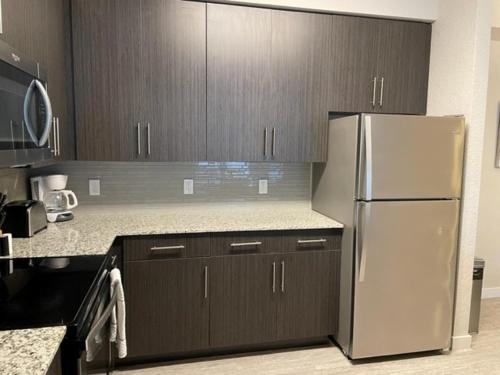 a kitchen with a stainless steel refrigerator and wooden cabinets at Stylish Modern 3bd-2ba With Amenities in Daytona Beach