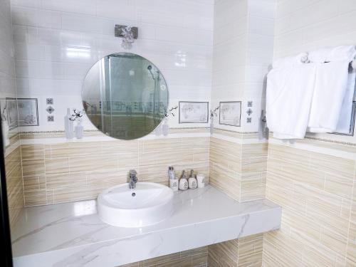 Hotel Quốc Hương في Chợ Phước Hải: حمام أبيض مع حوض ومرآة