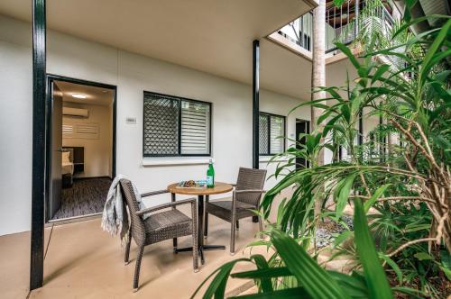 un patio con mesa, sillas y plantas en Palms City Resort en Darwin