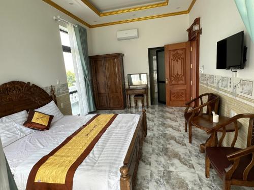 a bedroom with a bed and a tv and a chair at Hotel Quốc Hương in Chợ Phước Hải