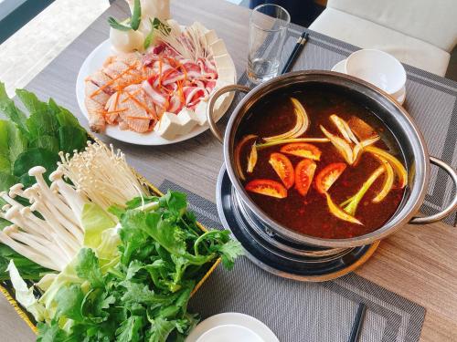 a pot of soup next to a plate of vegetables at Khách Sạn X2 Vibe Việt Trì in Làng Tiên Cát
