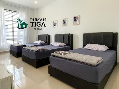 two beds in a room with a sign on the wall at Rumah Tiga Tingkat in Kuantan