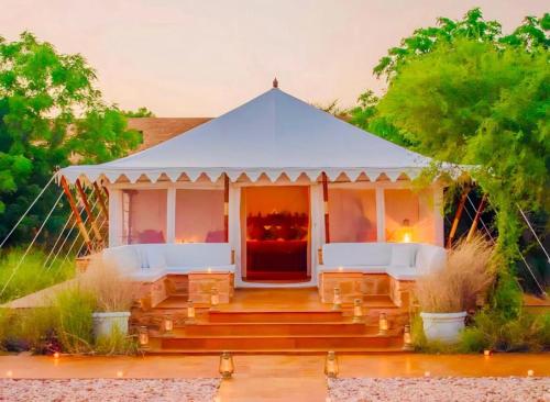 einen Pavillon mit zwei weißen Bänken davor in der Unterkunft Sam dunes desert safari camp in Jaisalmer