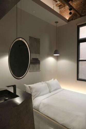 a bedroom with a white bed and a mirror at kodō hotel - Heart of LA Arts District in Los Angeles