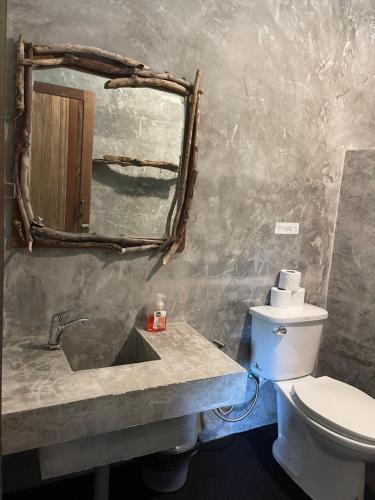 a bathroom with a sink and a toilet and a mirror at Groovy Bungalows Koh Phayam in Ko Phayam