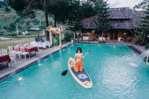 木州的住宿－The Nordic Village，妇女在游泳池里骑桨板