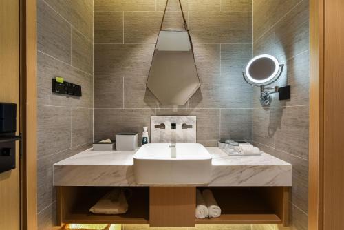 uma casa de banho com um lavatório e um espelho em Atour Hotel Beijing Chaoyangmen em Pequim