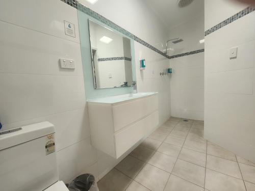 a white bathroom with a sink and a mirror at Motel24Seven and Apartments in Sale