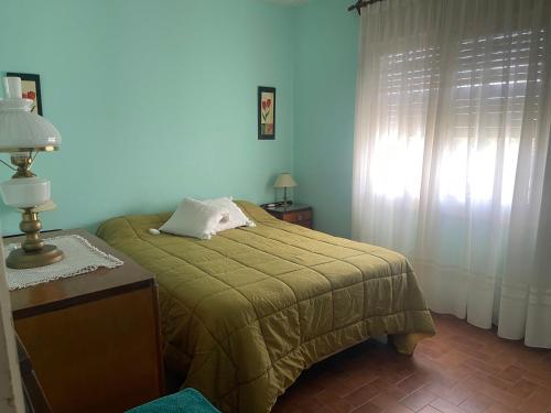 Un dormitorio con una cama con una manta verde y una ventana. en Casa Rosa, en Alta Gracia