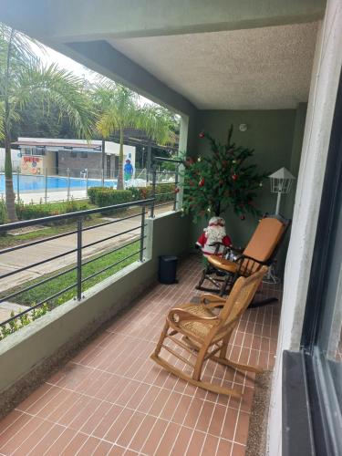een veranda met twee stoelen en een tafel met een plant bij Apartamento cómodo con todo lo que necesitas y con piscina in Ricaurte