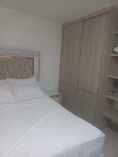 een slaapkamer met een wit bed en een kast bij Apartamento cómodo con todo lo que necesitas y con piscina in Ricaurte