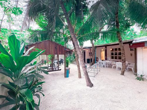 a patio with palm trees and a table and chairs at Ithaa Hiya Dhihfushi in Dhiffushi