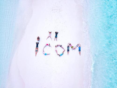 Un gruppo di persone che si trovano su una spiaggia formando la parola amore di iCom Marina Sea View a Maafushi