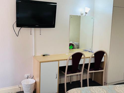 a desk with two chairs and a television on a wall at Jacksons Motor Inn in Adelaide