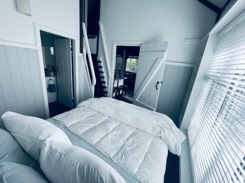 a bedroom with a white bed and a staircase at Experience Heritage, Live Modern in Upper Hutt