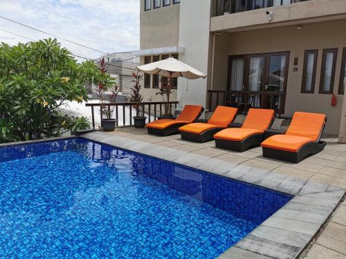 una piscina con tumbonas naranjas y sombrilla en Bukit Jaya Residence & Apartment Semarang en Semarang