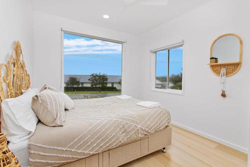 a white bedroom with a bed and a large window at Prime Position in Gerroa