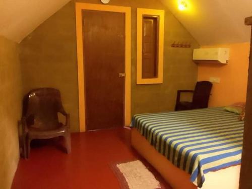 ein Schlafzimmer mit einem Bett, einem Stuhl und einer Tür in der Unterkunft By The C' Cabanas in Hikkaduwa