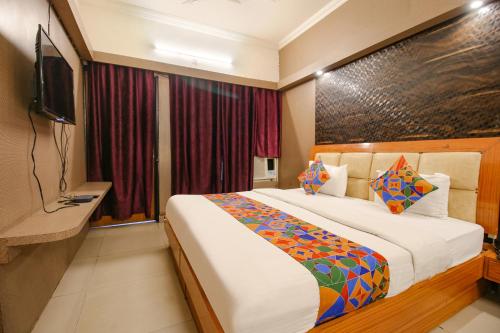 a hotel room with a bed and a flat screen tv at FabHotel Neena Palace in Bhopal