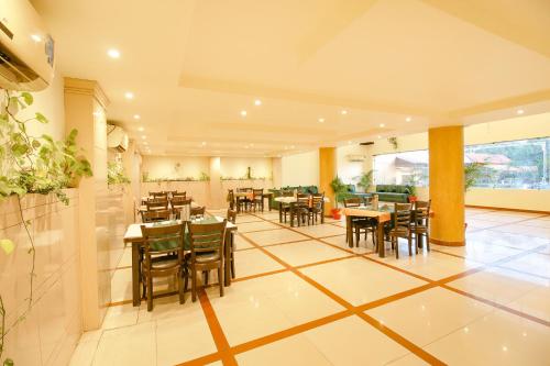 Un restaurante con mesas y sillas en una sala. en FabHotel Neena Palace, en Bhopal