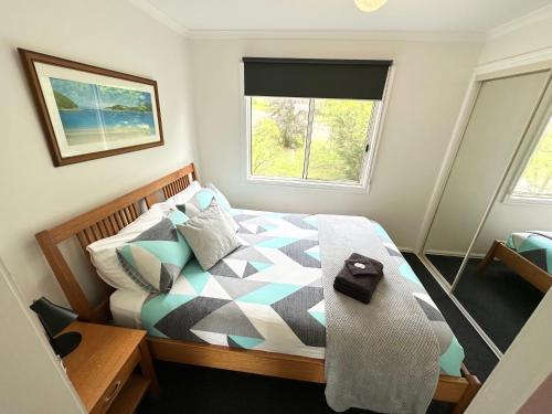 a bedroom with a bed and a window at Tidal Dreaming Seaview Cottages in Yanakie