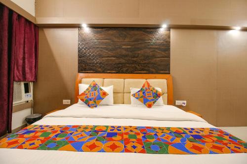 a bedroom with a large bed with a colorful quilt at FabHotel Neena Palace in Bhopal