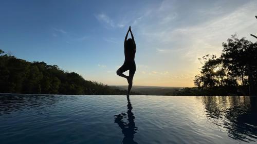 a woman doing a yoga pose in the water at Rajaklana Resort and Spa in Bantul