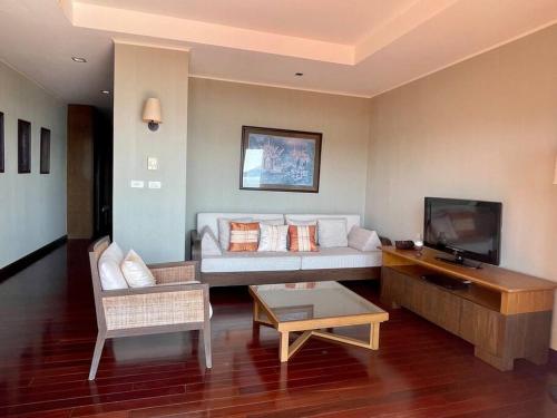 a living room with a couch and a tv at Panoramic sea view, 1 bed flat in Ban Bang Bao