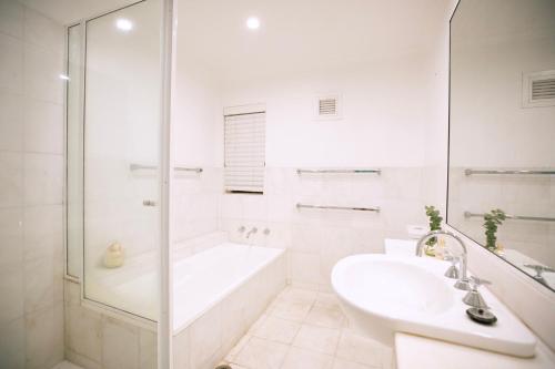 uma casa de banho branca com uma banheira e um lavatório em Central New York Style Warehouse em Sydney