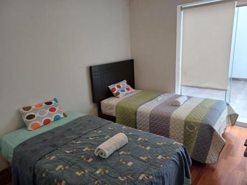 2 camas en una habitación pequeña con ventana en Habitación acogedora Aramburú, en Lima