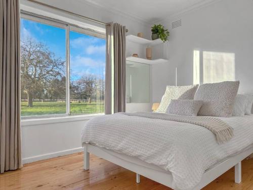 a white bedroom with a bed and a large window at 'Hawthorn Park' Farm Homestead in Macedon Ranges in Romsey