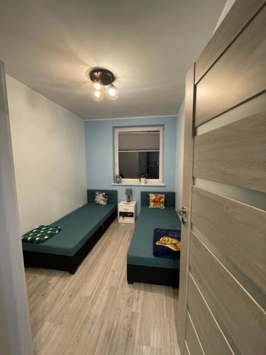 um pequeno quarto com duas camas e uma porta em Apartament Kosakowo em Kosakowo
